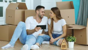 Young couple sitting on floor using tablet computer after relocation in their new house